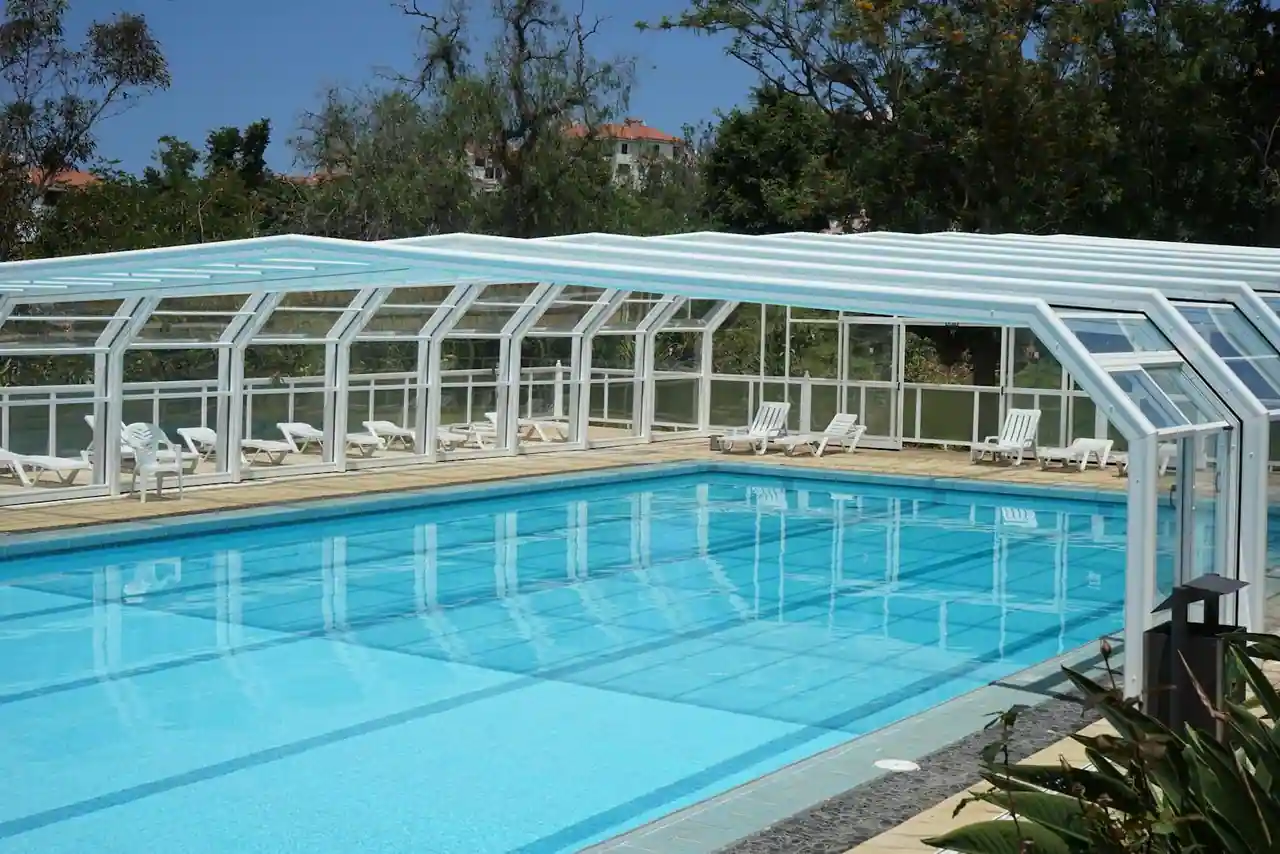 Abri de piscine télescopique en aluminium et polycarbonate couvrant un bassin dans un jardin