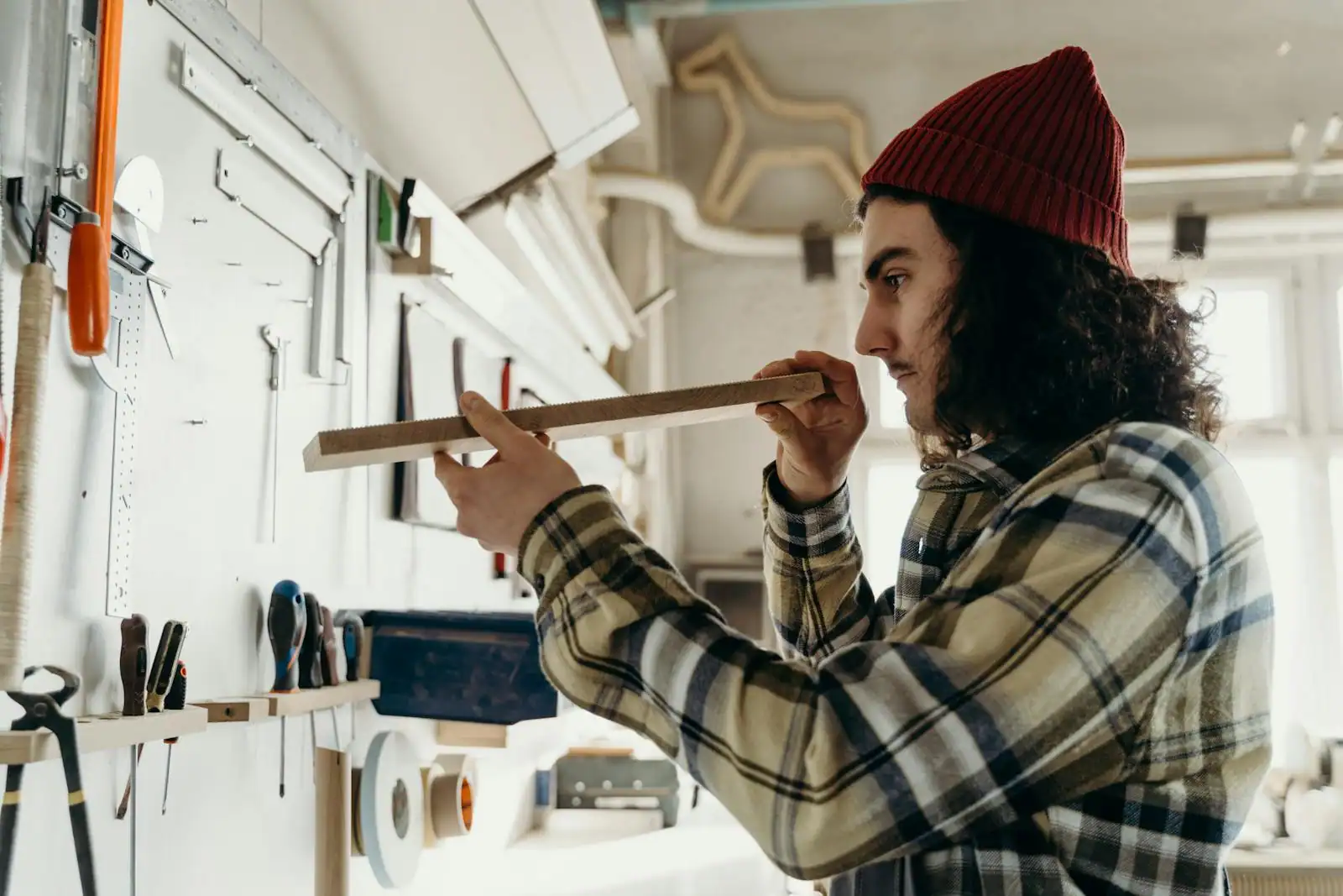 Menuisier dans son atelier traçant des mesures sur un panneau de bois pour un meuble sur mesure
