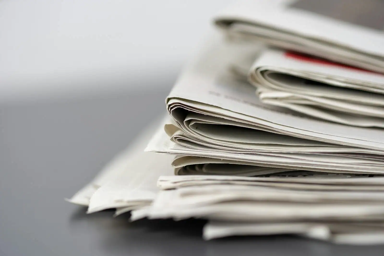 Pile de journaux pliés empilés sur une table, en gros plan, illustrant l'actualité du jour