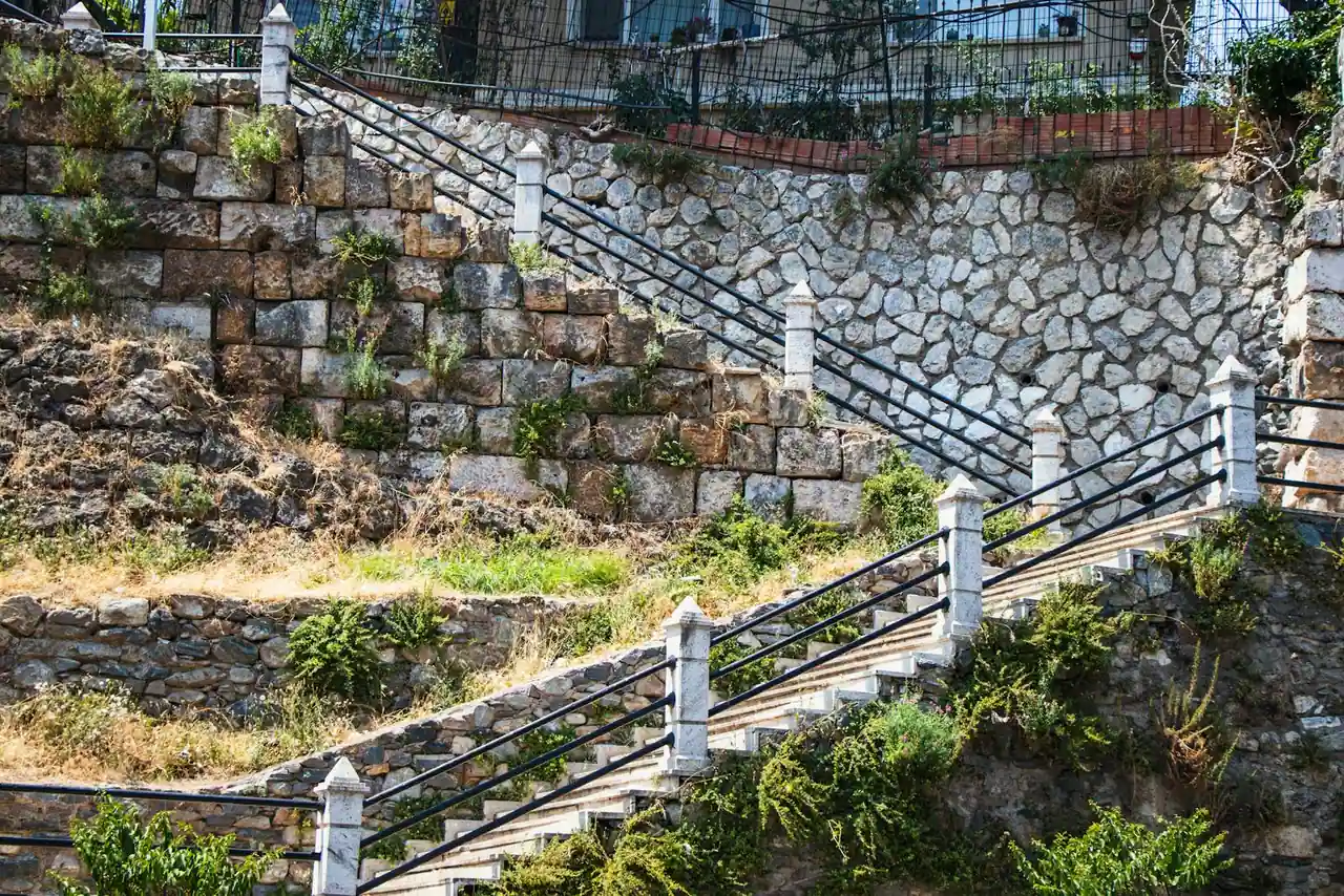 Terrain en pente aménagé avec des murs de soutènement en pierre et un escalier reliant les paliers.