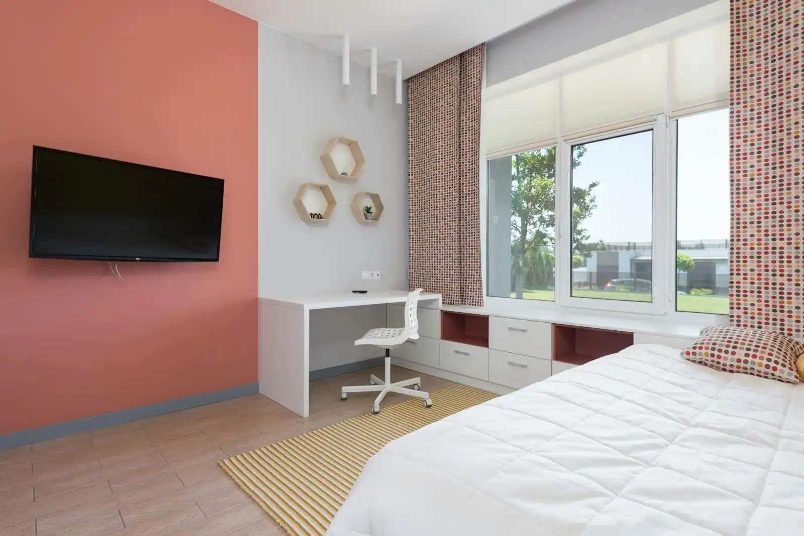 Chambre d'adolescent lumineuse avec lit, coin bureau près de la fenêtre et étagères de rangement