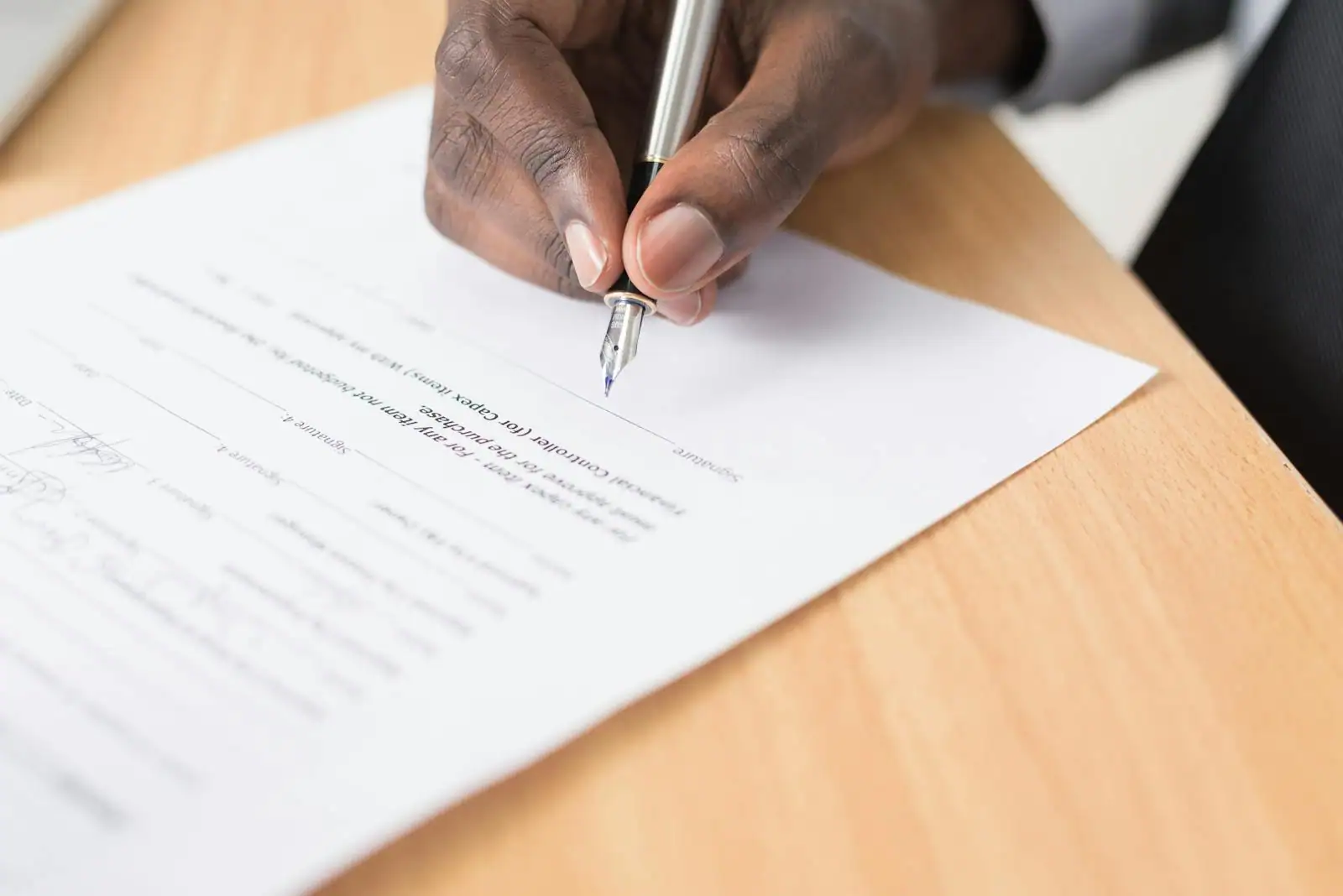 Main signant un contrat au stylo, documents posés sur un bureau