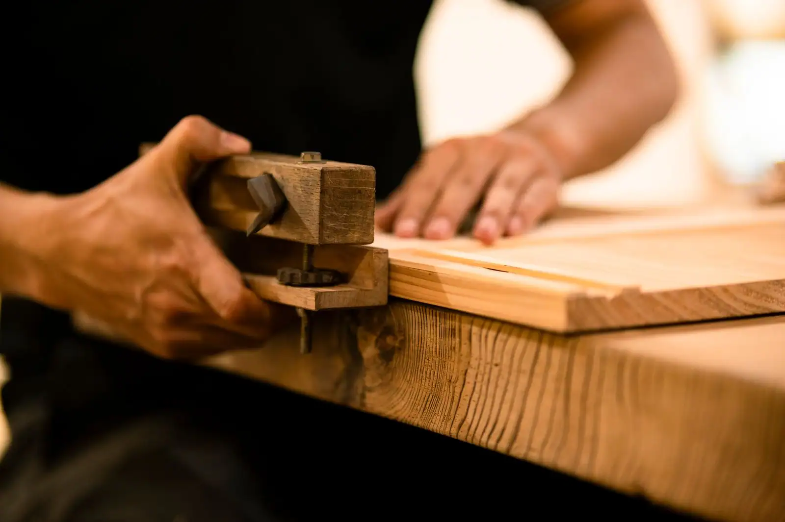 Un artisan menuisier travaille le bois dans son atelier, copeaux et outils à la main