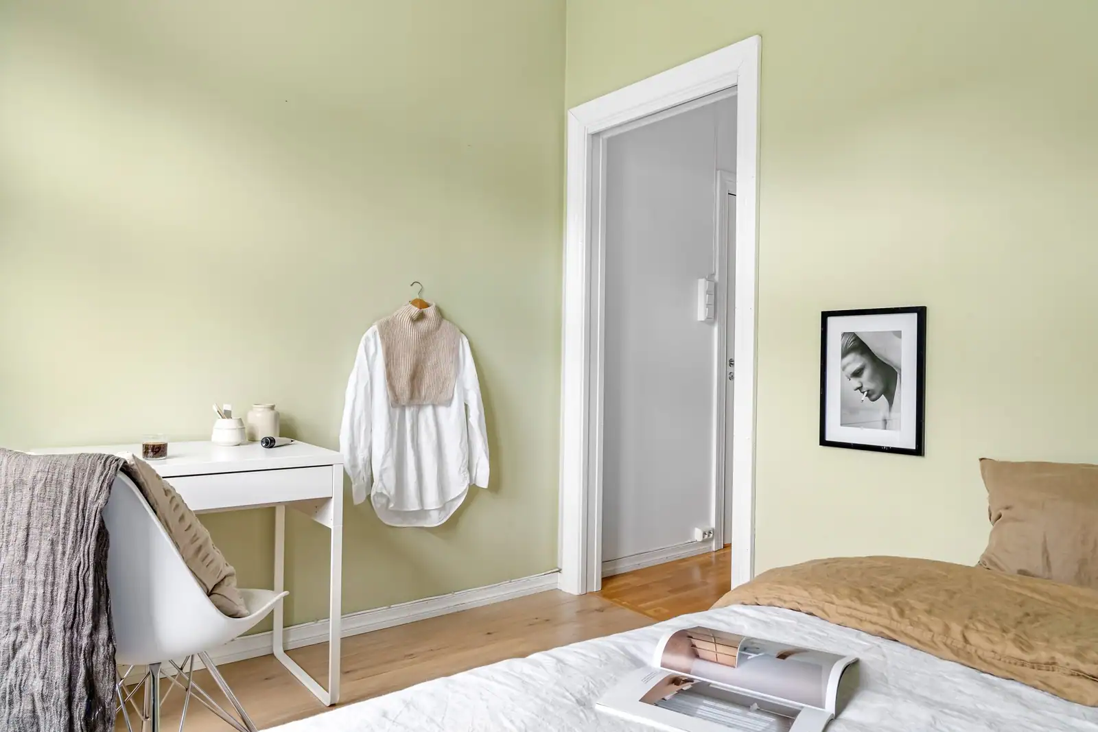 Chambre d'adulte apaisante aux murs vert doux, avec lit en lin, bureau blanc et parquet clair.