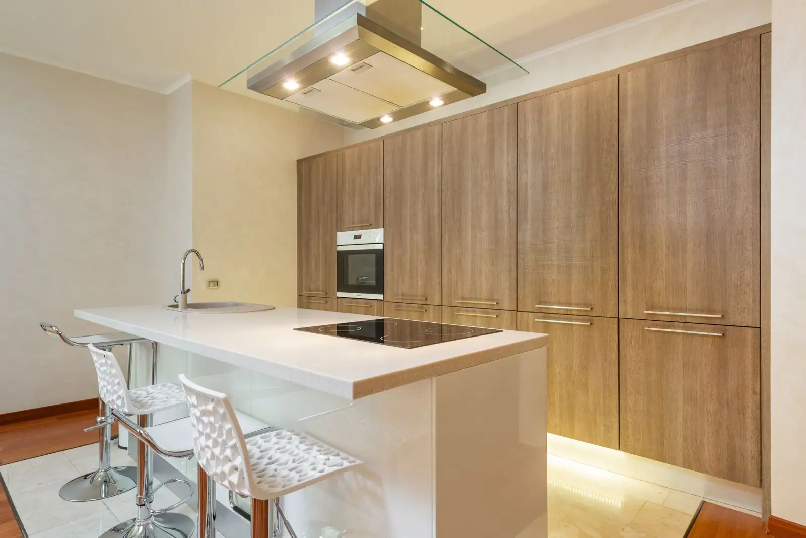 Cuisine contemporaine avec îlot central, plan de travail blanc et meubles en bois clair.