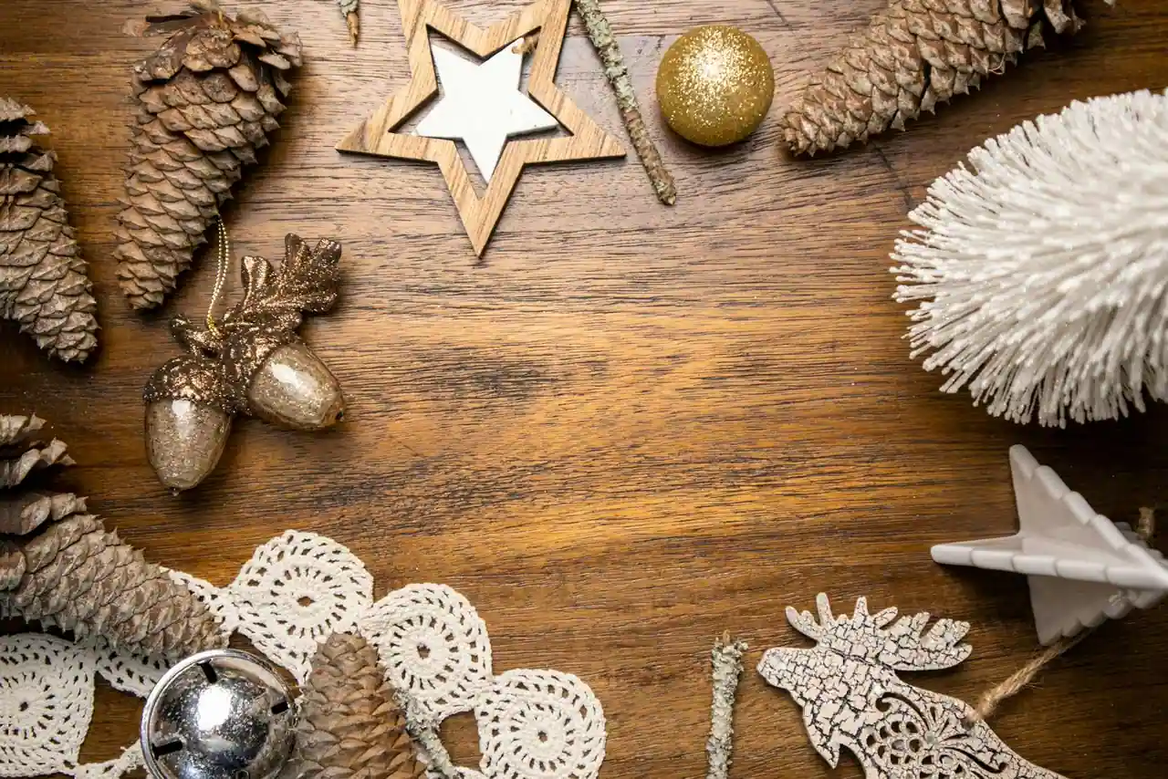 Décorations de Noël faites main posées sur une table en bois : couronne de verdure, pommes de pin et bougies