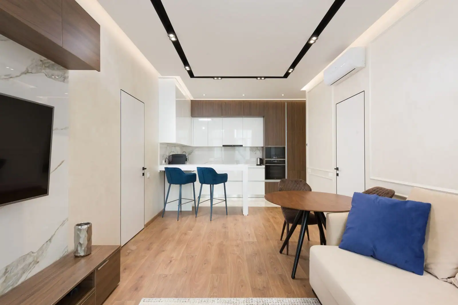 Salon ouvert d'un appartement meublé moderne, canapé, coin repas et cuisine équipée, prêt pour la location