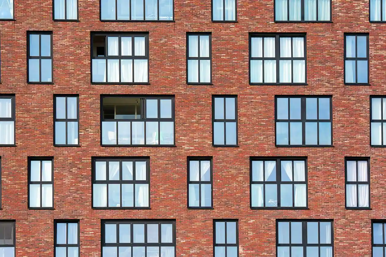 Façade en brique rouge d'un immeuble d'habitation aux fenêtres alignées, illustration d'un bien en location
