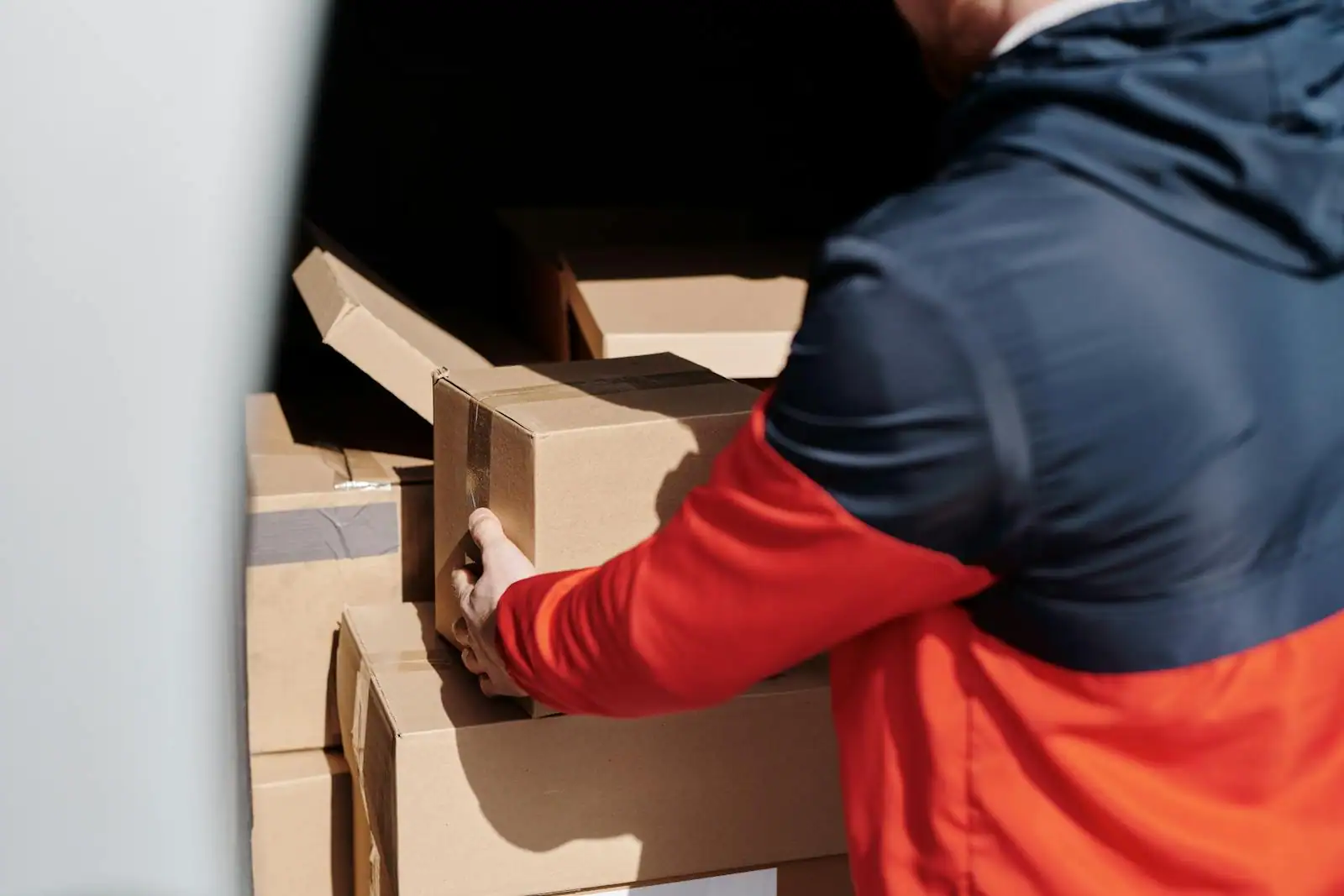 Personne chargeant des cartons de déménagement dans un fourgon utilitaire blanc