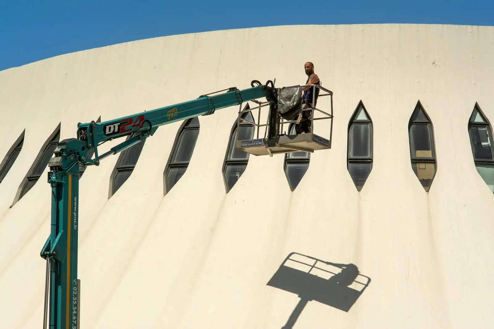 Opérateur travaillant sur une nacelle élévatrice près d'une façade de bâtiment