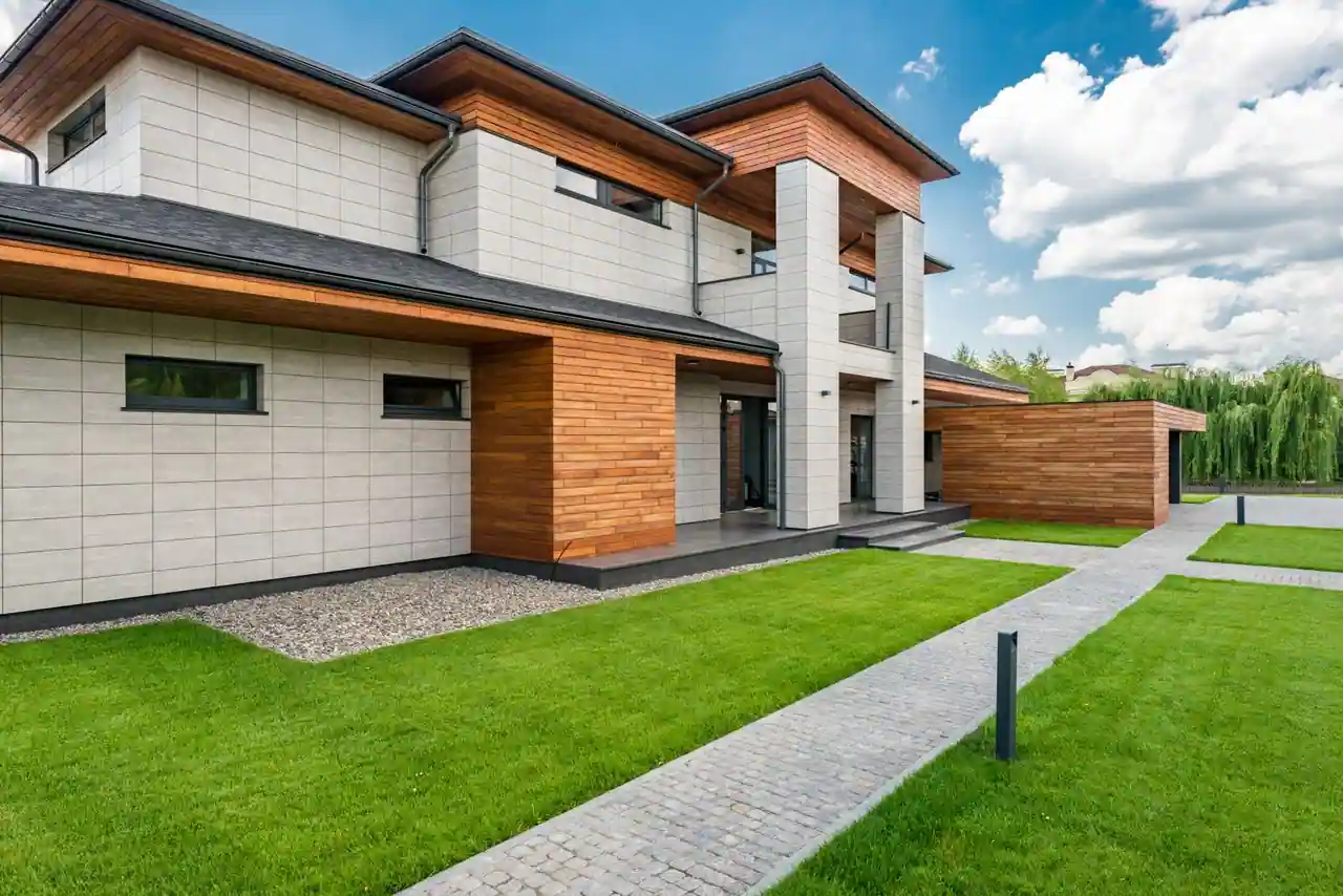 Maison contemporaine moderne vue de l'extérieur, façade en pierre et bois, pelouse et allée pavée