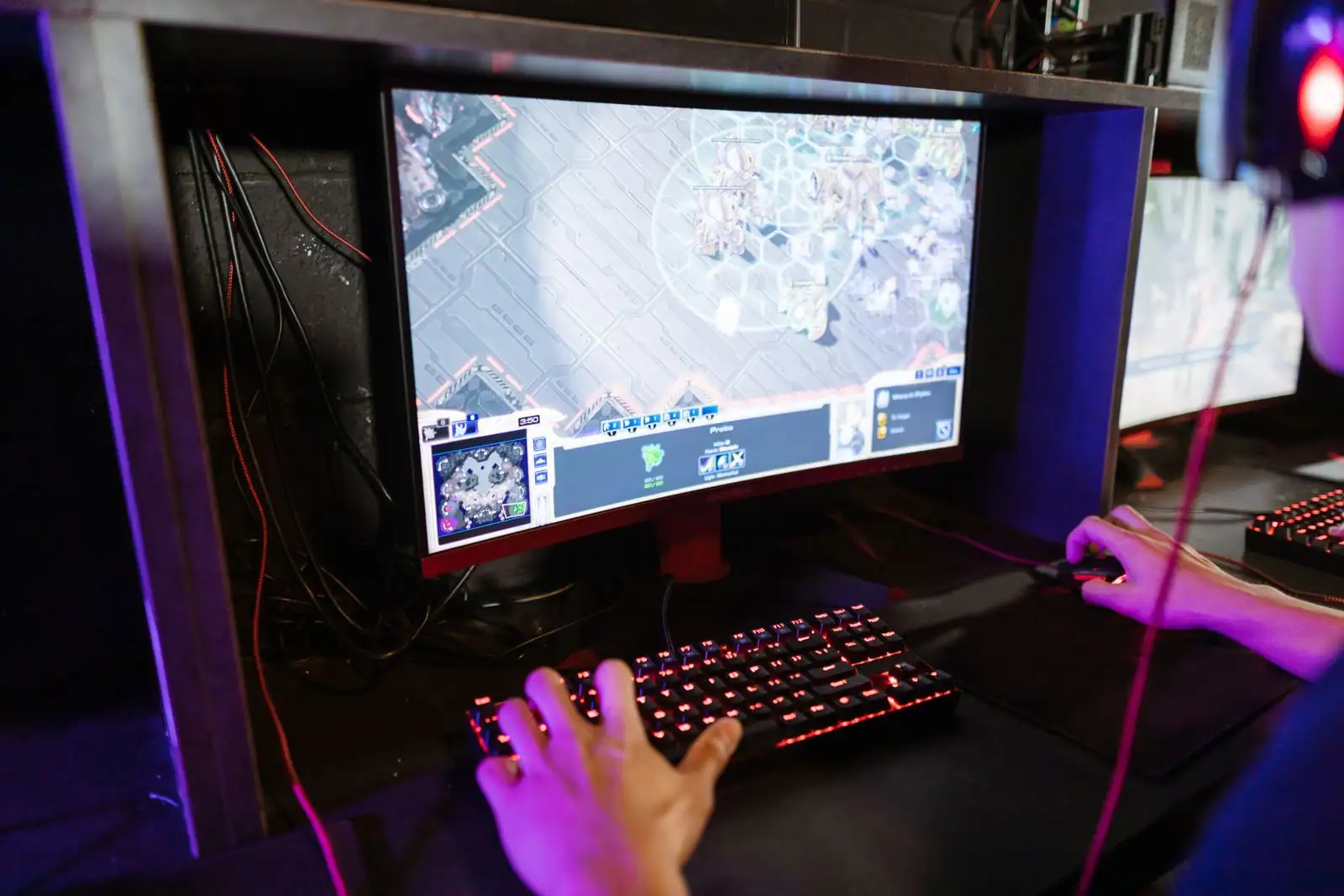 Joueur sur PC, mains sur clavier et souris, devant une partie de jeu vidéo en ligne (image illustrative)