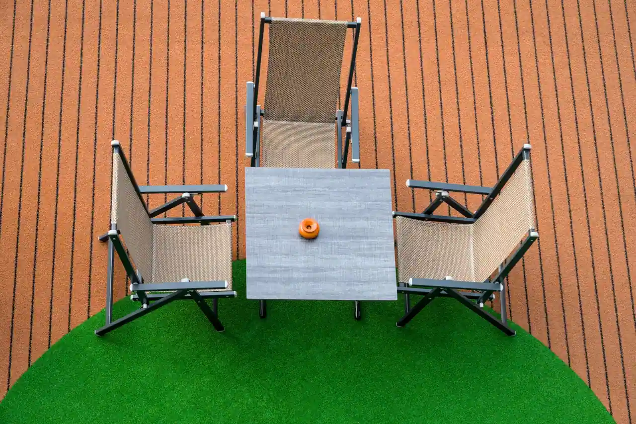 Table et chaises de jardin en textilène disposées sur une pelouse, vue de dessus