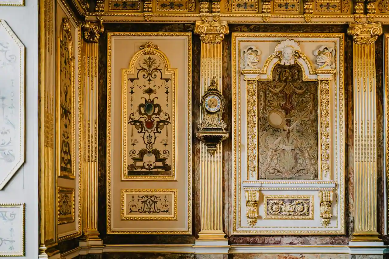 Intérieur patrimonial aux boiseries dorées, orné d'un panneau de tapisserie et d'une pendule ancienne.
