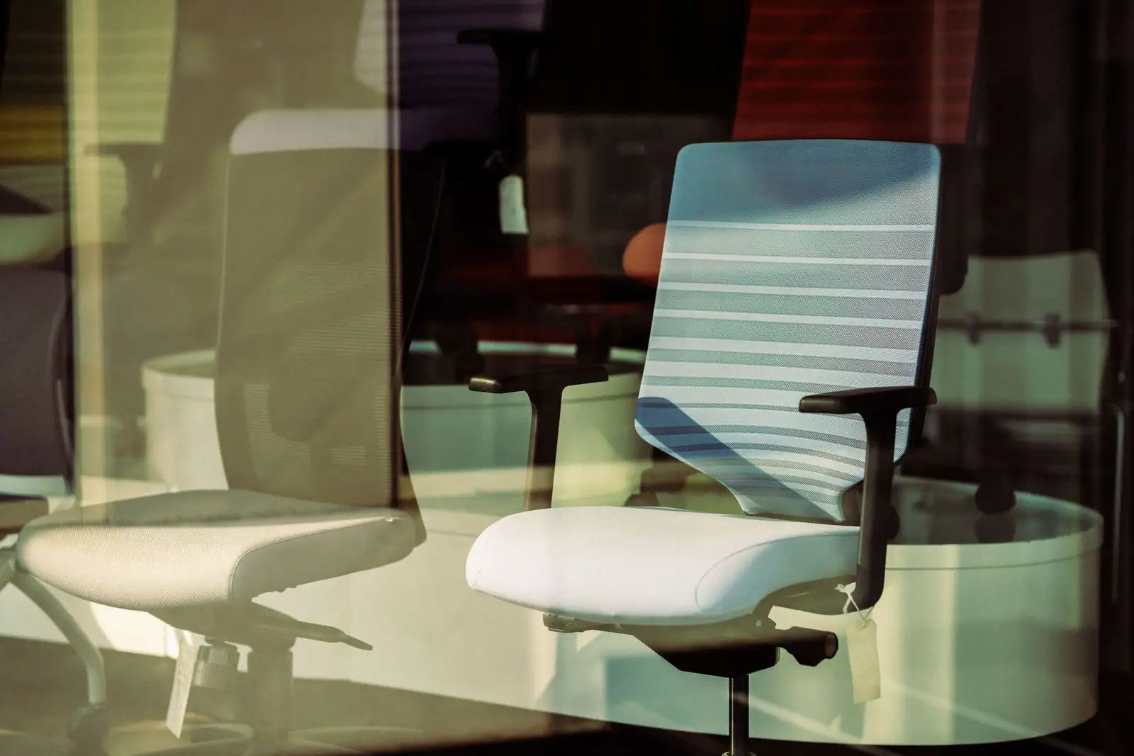 Sièges de bureau ergonomiques exposés derrière une vitrine, exemple de mobilier professionnel