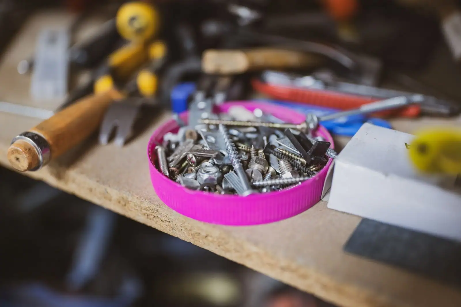 Boîte de vis et chevilles entourée d'outils à main sur un établi d'atelier