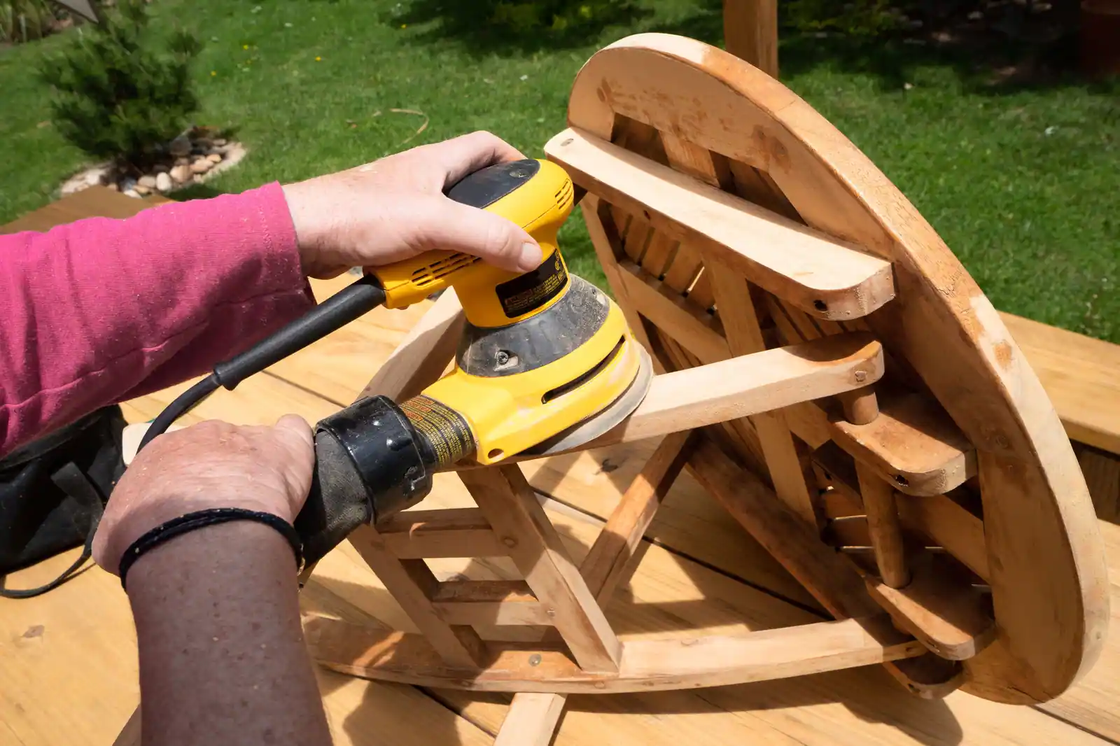 Rénovation d'un meuble en bois : ponçage de la surface à la ponceuse électrique, en extérieur