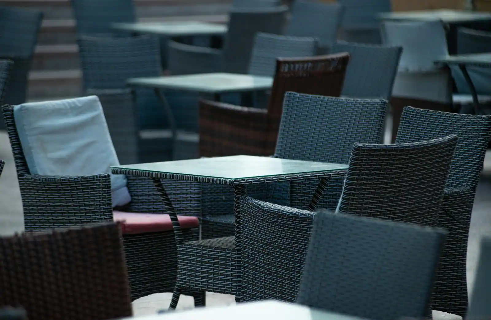 Fauteuils et tables en résine tressée gris foncé disposés sur une terrasse extérieure