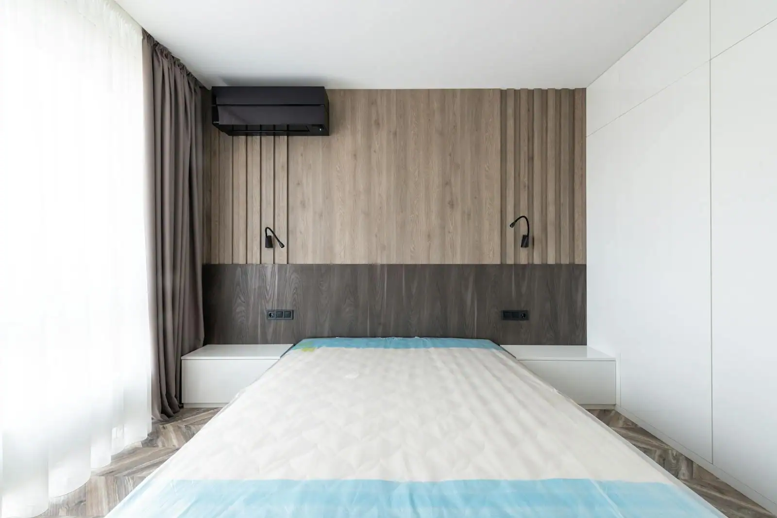 Chambre d'adulte aux tons neutres et chaleureux, avec tête de lit en bois, linge en lin et éclairage doux.