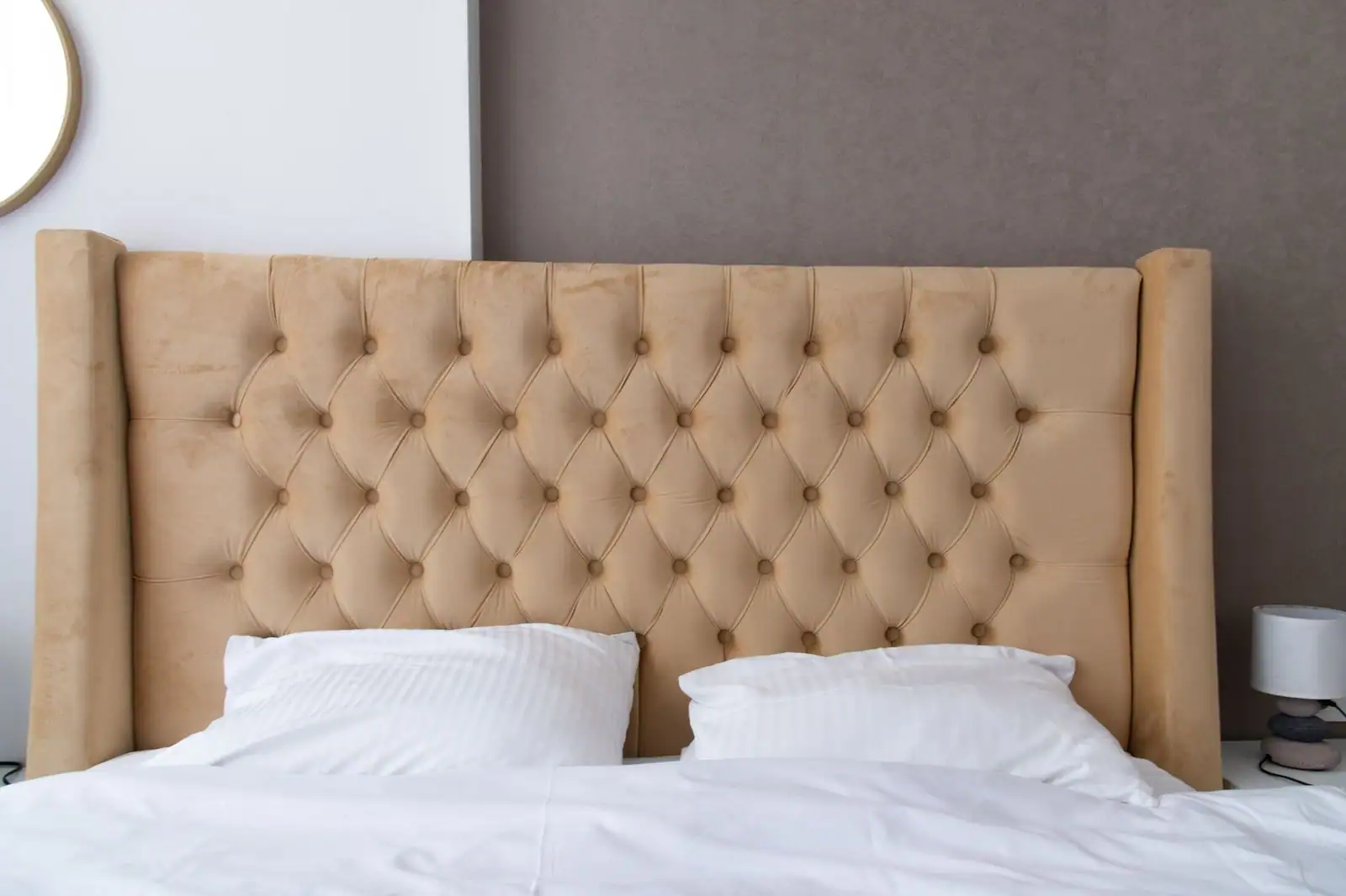 Tête de lit capitonnée installée au-dessus d'un grand lit dans une chambre moderne et épurée