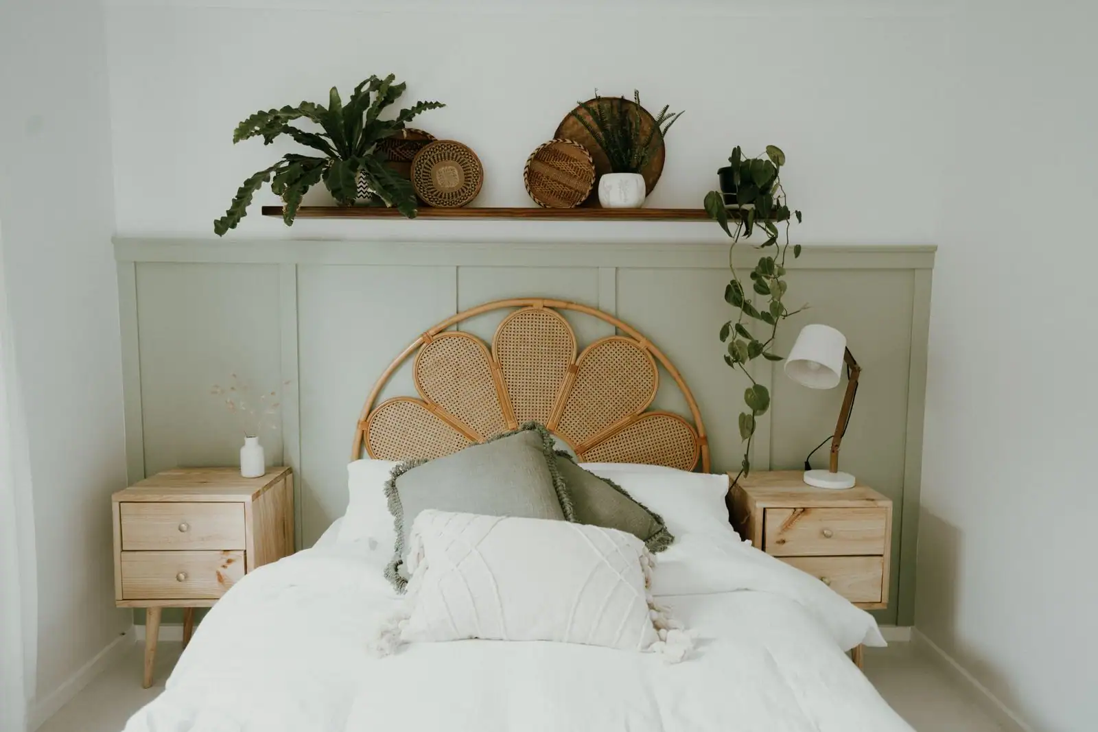 Chambre claire avec une tête de lit en rotin au cannage en forme de pétales, au-dessus d'un lit en linge blanc