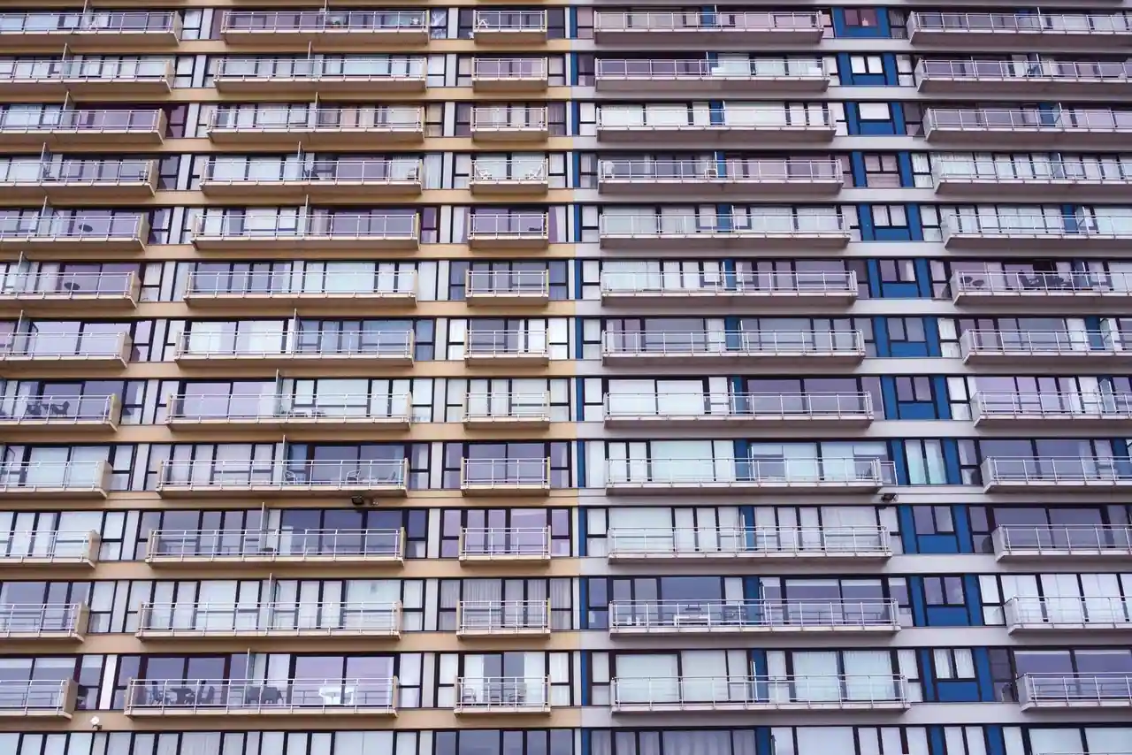 Façade d'un immeuble résidentiel moderne avec balcons et grandes fenêtres dans un quartier urbain
