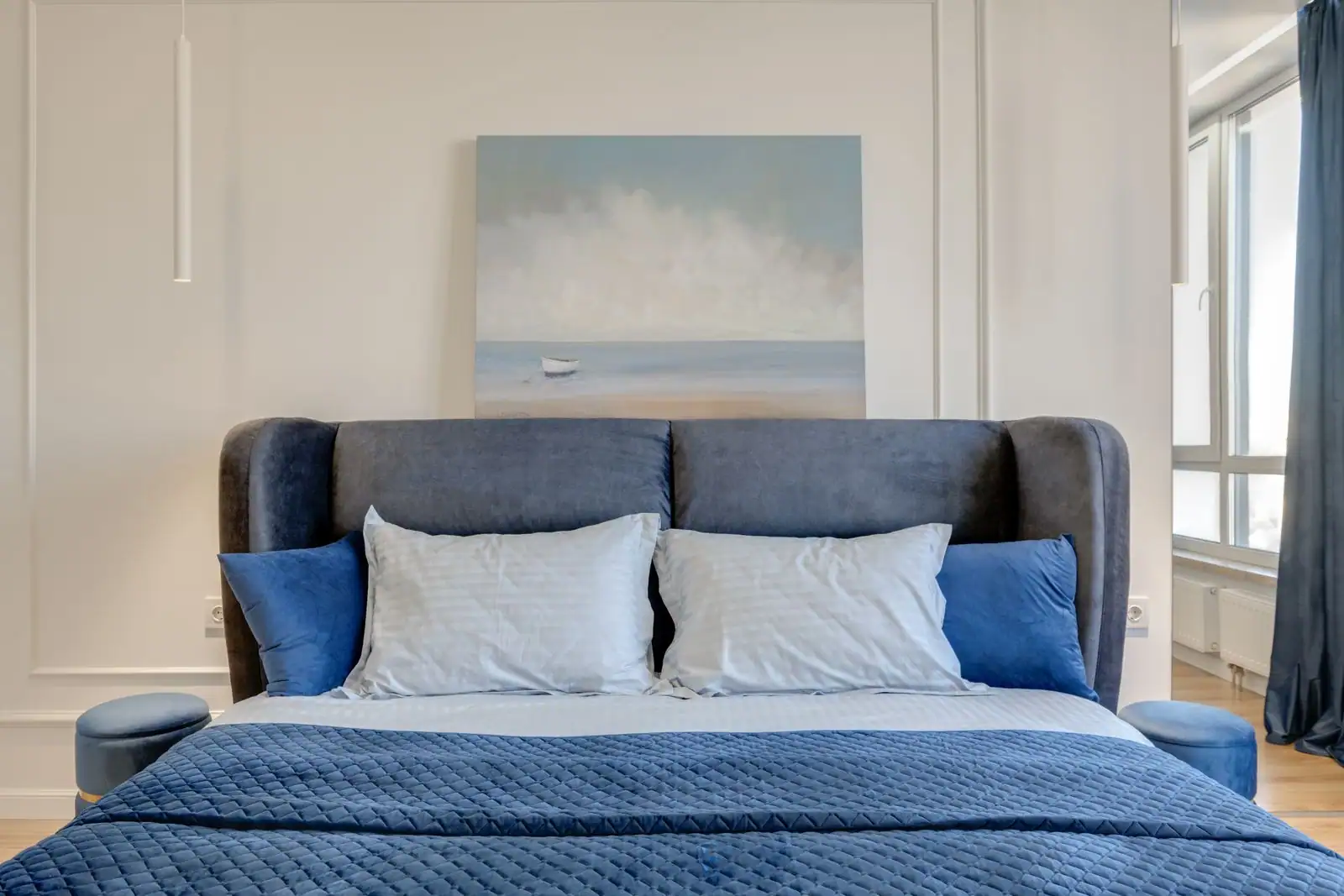 Chambre à coucher soignée avec lit double, oreillers et fenêtre, dans une maison lumineuse.