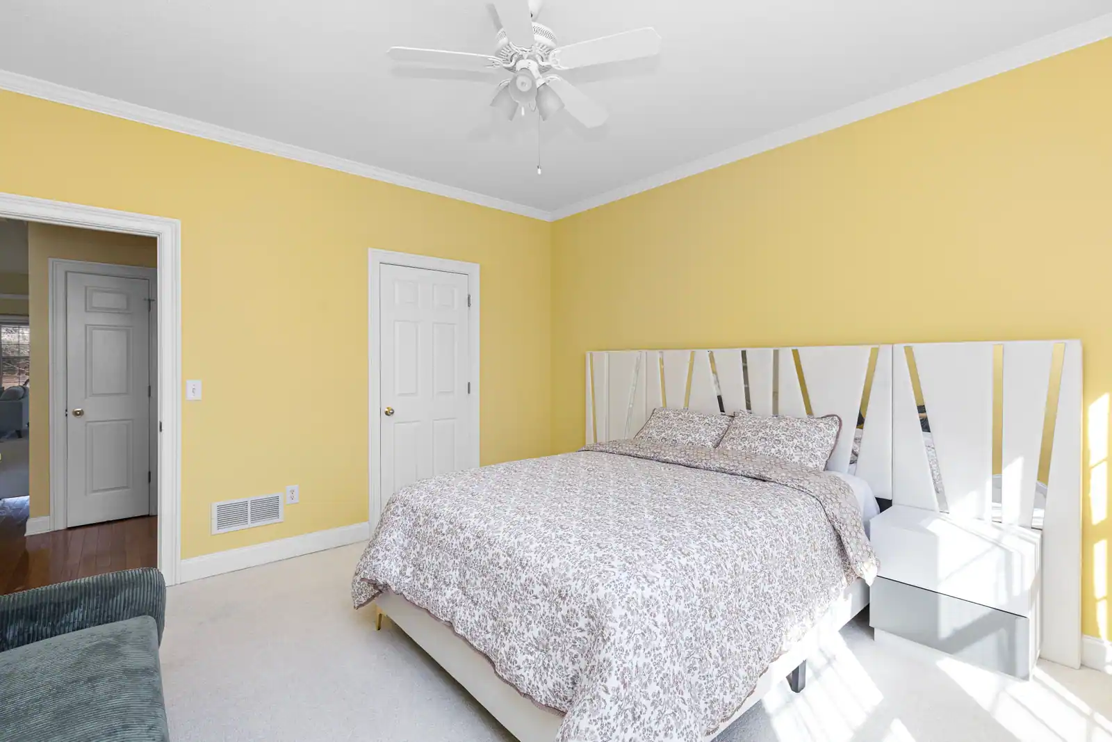 Chambre aux murs jaune doux avec mobilier blanc, lit double et lumière naturelle abondante