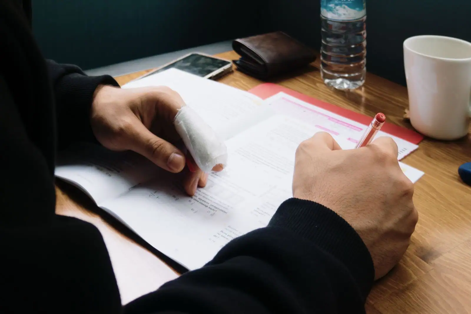 Main dont un doigt est entouré d'un pansement de gaze, posée sur une table de travail.
