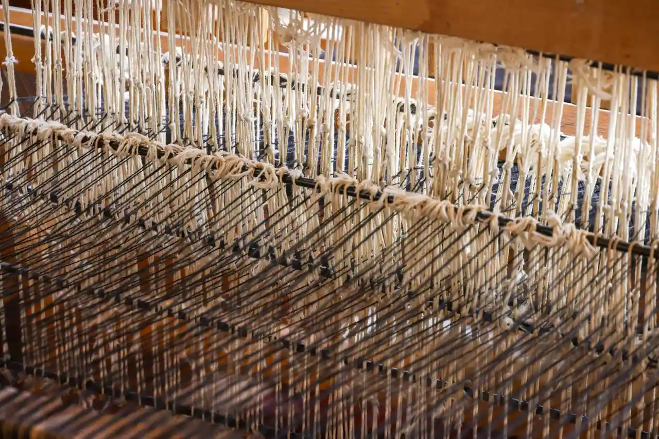 Métier à tisser en bois aux fils de laine clairs tendus, dans un atelier de tissage artisanal.