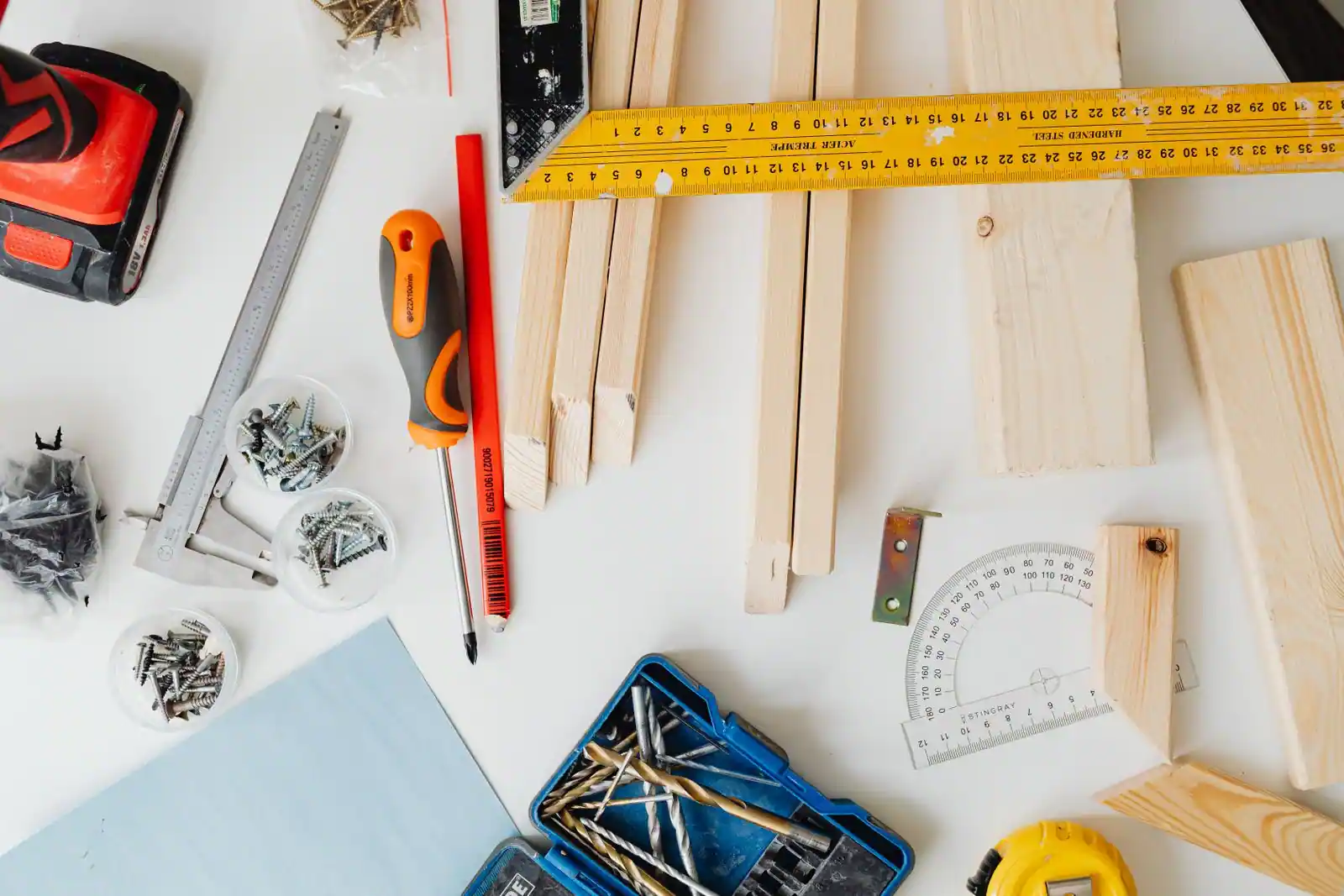 Outils de bricolage et pièces de bois disposés sur un plan de travail clair, prêts pour un projet à faire soi-même.