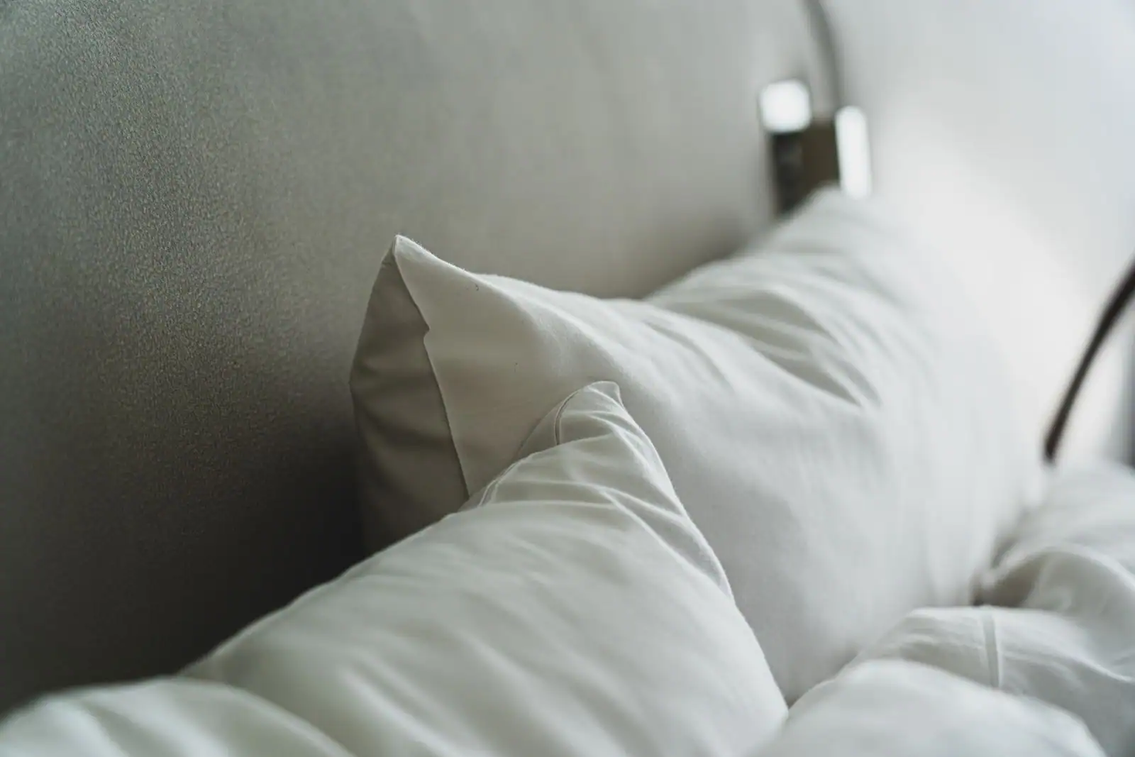 Chambre lumineuse et épurée avec un lit superposé de linge blanc et des oreillers empilés, ambiance hôtel-boutique.